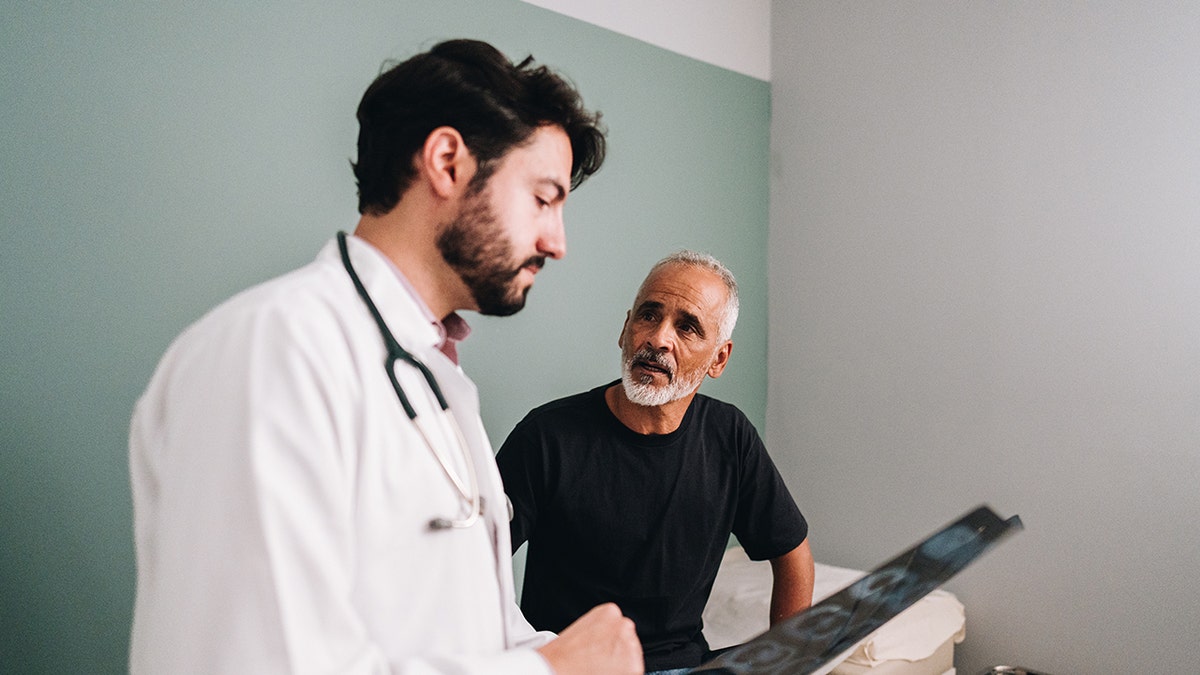 Doctor talking to his patient while showing an image of X rays to the doctor. To use -in pieces on prostate cancer projections