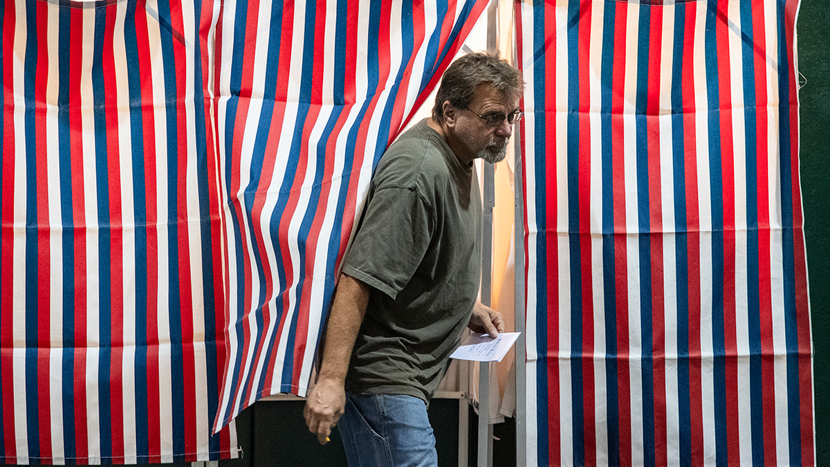 A man comes out of a voting stand.