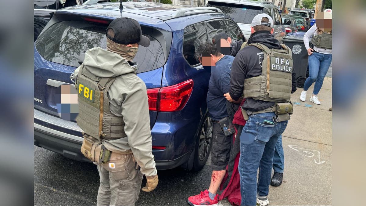 The suspect arrested by car is blurred in a federal raid